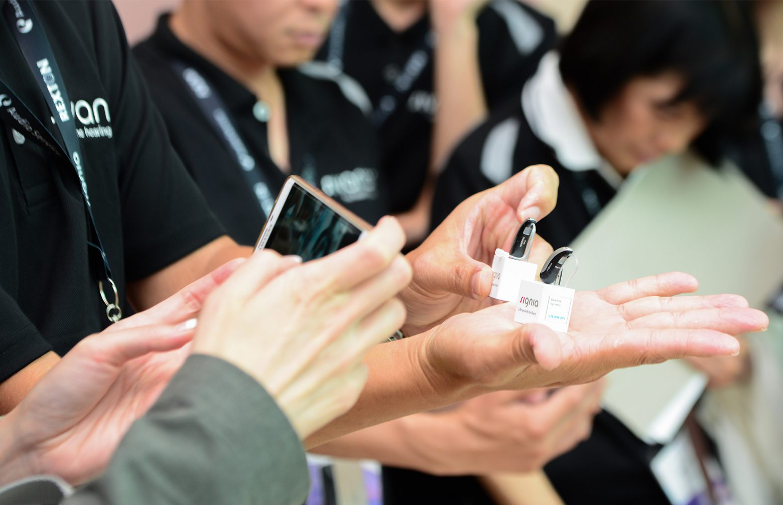 Sivantos employees holding Signia hearing aids